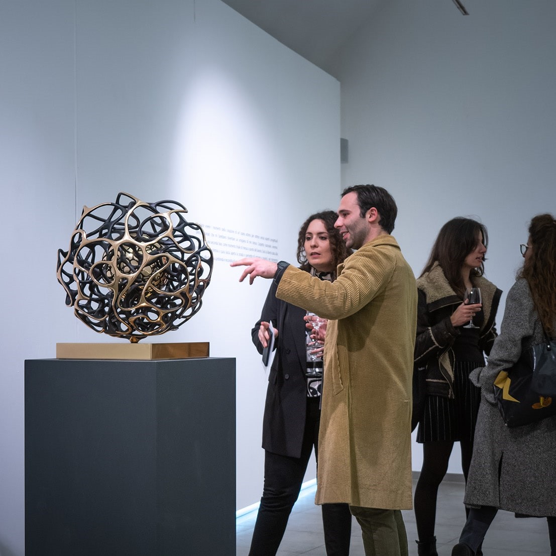 Visitors interacting with Sfera Cabala by Gianfranco Meggiato, emphasizing its detailed craftsmanship.